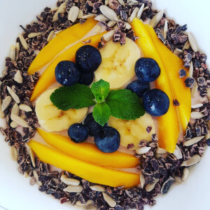 Breakfast bowl of oats, mango, blueberries and cocoa nibs.