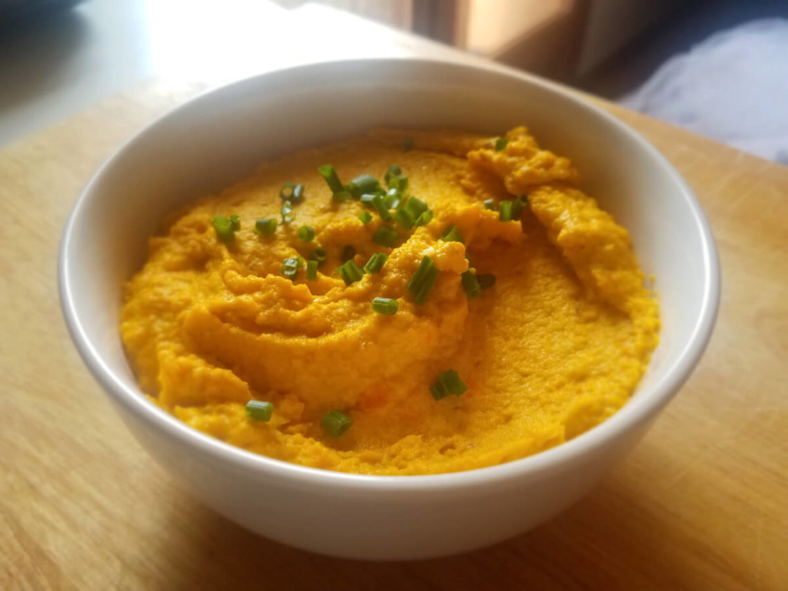 Carrot hummus garnished with chives or coriander.