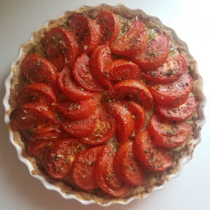 A freshly baked leek and dill tart topped with roasted tomatoes.